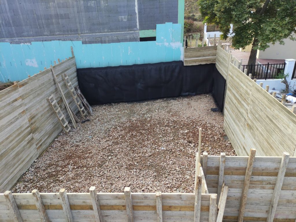 The gravel layer at the bottom and the black membrane on the sides of the pit.