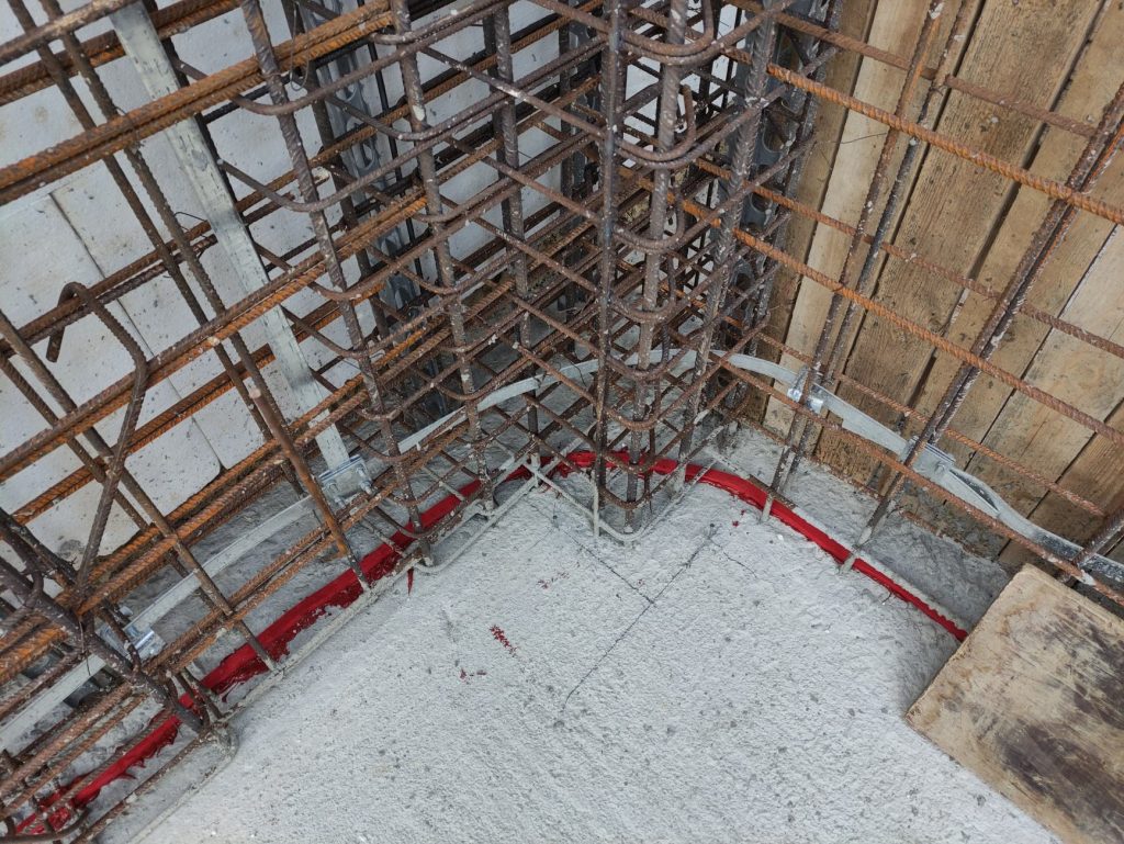 The reinforcement at the corner of the basement walls, with red waterproofing tape on the joint with the raft foundation.