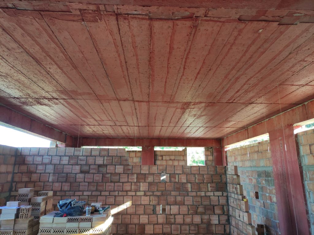 The ground-floor clay brick walls beneath the slab.