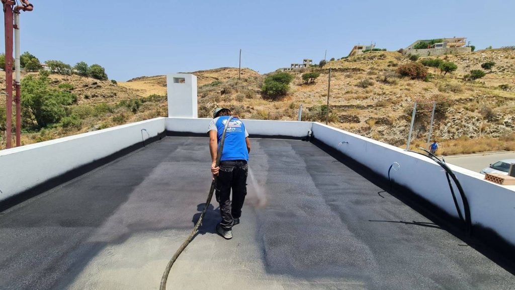 Applying waterproofing to the roof terrace, between the white parapets.