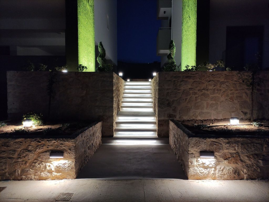 The lit entrance, with steps between stone planters.