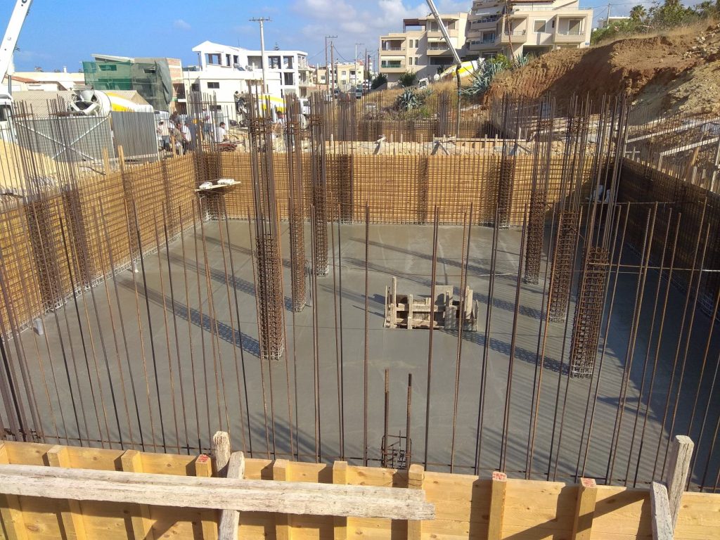The raft foundation after the concrete pour, with the column reinforcement and the wall formwork.