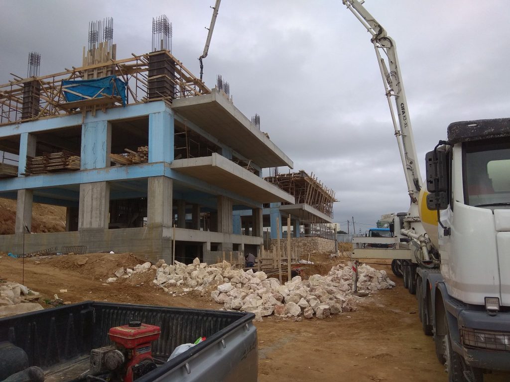 A concrete pump beside the building while a floor is being poured.