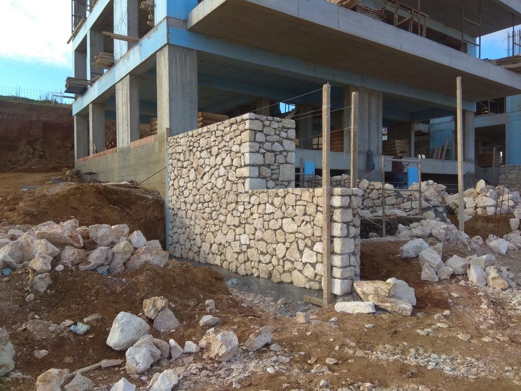 Stonework at the base of the building, with the stones on the ground around it.