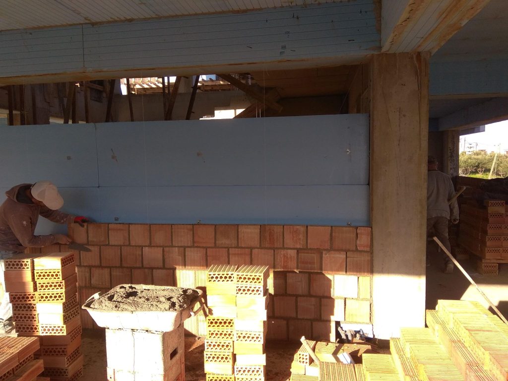 A crew building the walls with clay bricks.