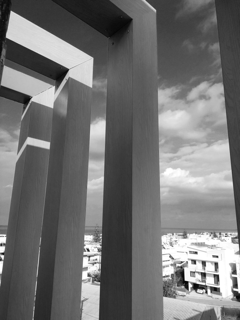 The pergola's vertical louvres in black and white, with the town in the background.