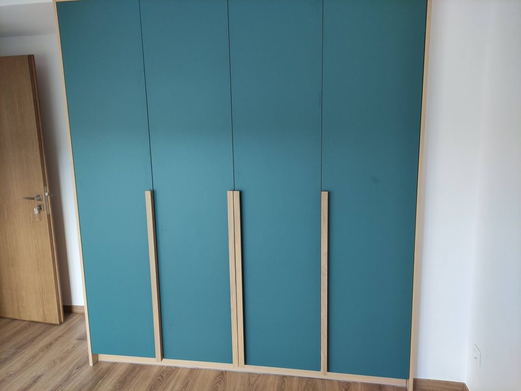 A built-in wardrobe with petrol-blue doors and wooden handles.