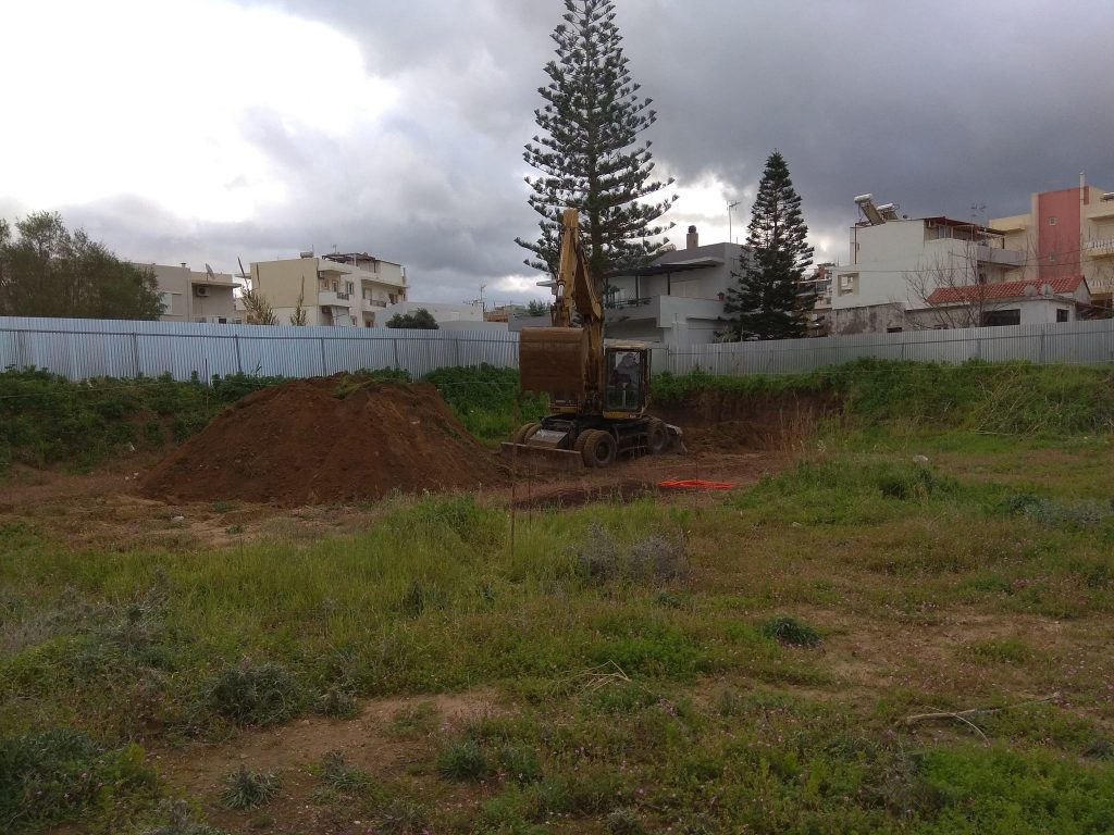 The plot at the start of excavation, with the excavator inside the site fence.