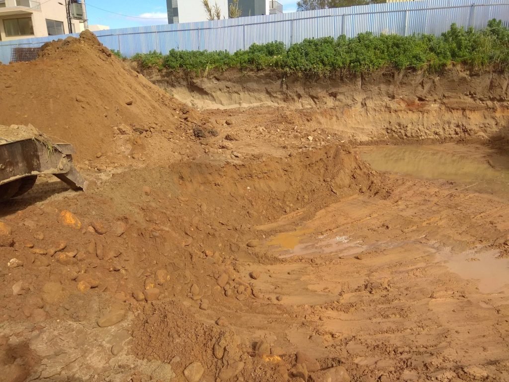 The excavator and the excavated soil inside the pit.