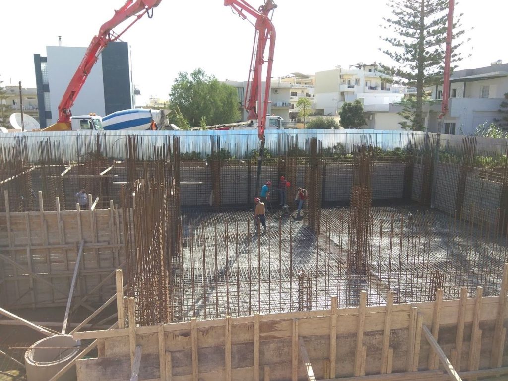 The raft foundation pour under way, with the pump and the concrete mixer truck in the street.