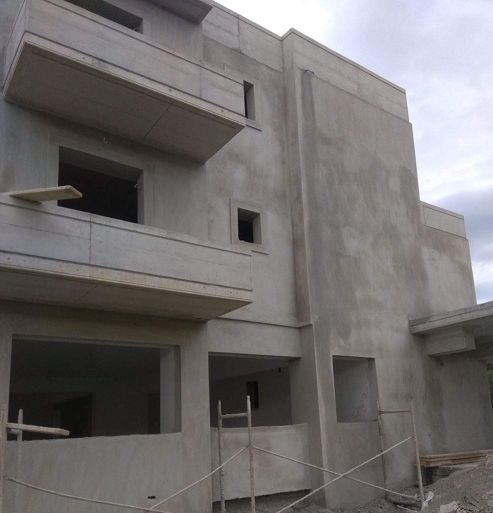 Side view of the building with the first coats of plaster on the walls and balconies.