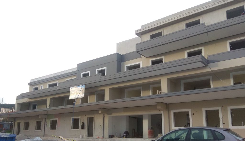 The front of the building after painting, in shades of beige and grey.