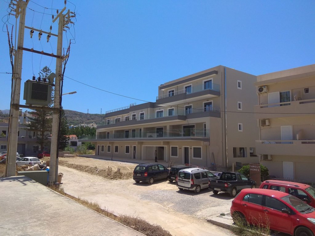 The completed building, seen from the street side with the parking area.
