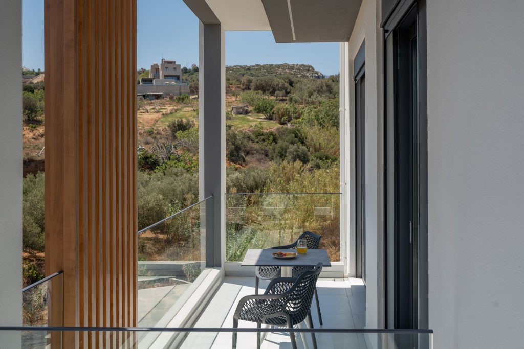 A balcony looking out to the olive-covered hills, behind a timber louvre.