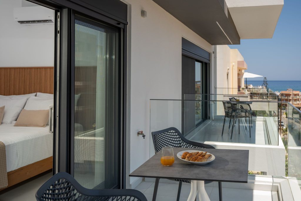 A glass-railed balcony outside the bedroom, with a sea view.