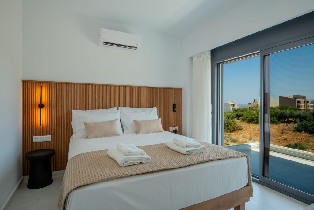 A bedroom with a timber-clad headboard wall and sliding glass doors onto the balcony.