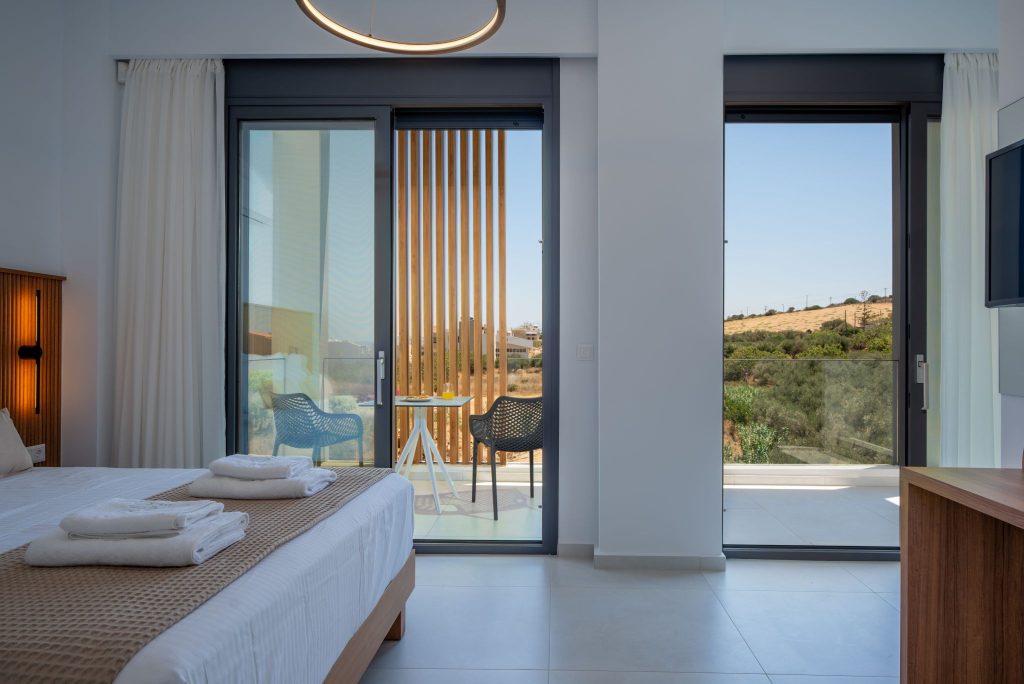 A bedroom with two French doors onto the balcony and a view of the hills.
