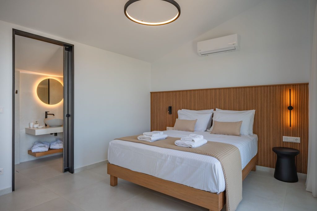 A bedroom with a wooden headboard and an open door to the bathroom.