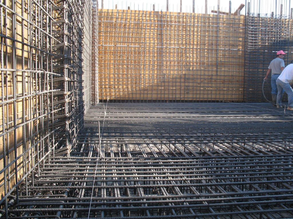 A crew on the foundation reinforcement, with the wall reinforcement around it.