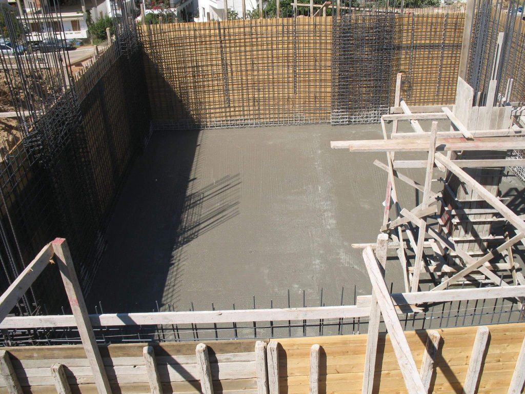 The foundation after the concrete pour, with the reinforcement of the basement walls around it.