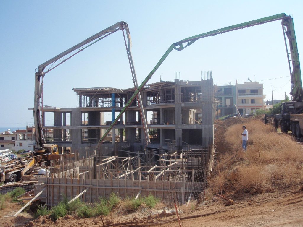 Two concrete pumps above the site, with the load-bearing structure rising in the background.