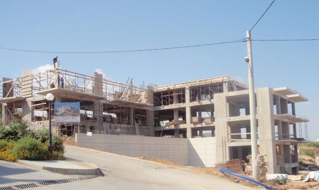 The load-bearing structure from the street, with the formwork for the next floor and the project sign.