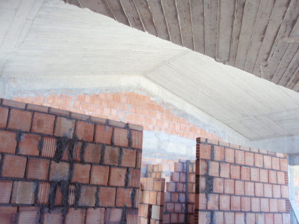 Brick walls beneath the sloping concrete roof of the top floor.