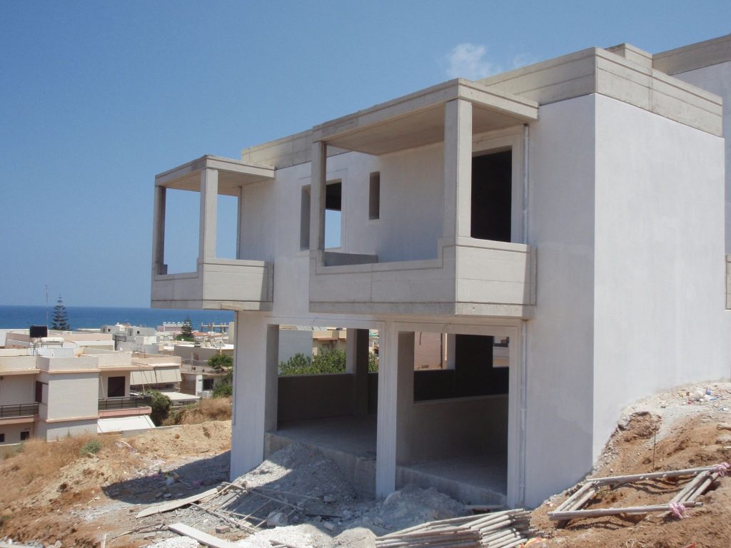 The pilotis and balconies of one wing after plastering, with the sea in the background.