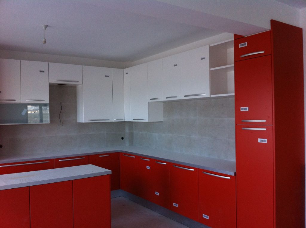 An apartment kitchen with red and white cabinets, shortly before handover.
