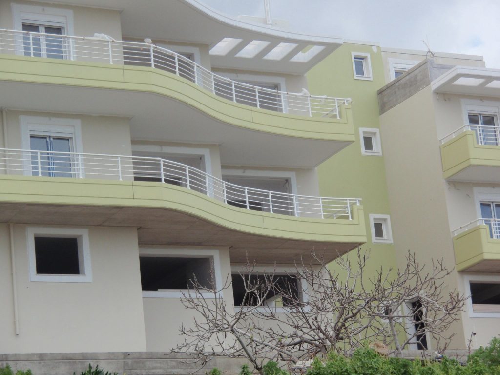 The curved balconies with white railings and the top-floor pergola.