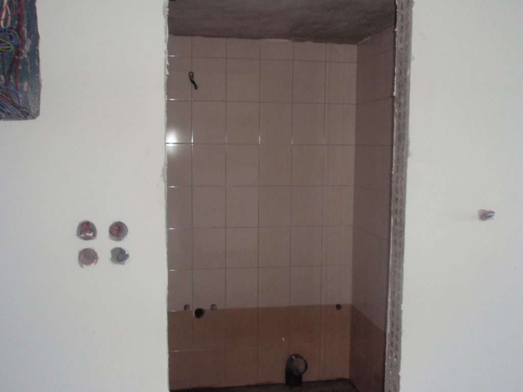 Tiling the bathroom, with the plumbing connection points in place.