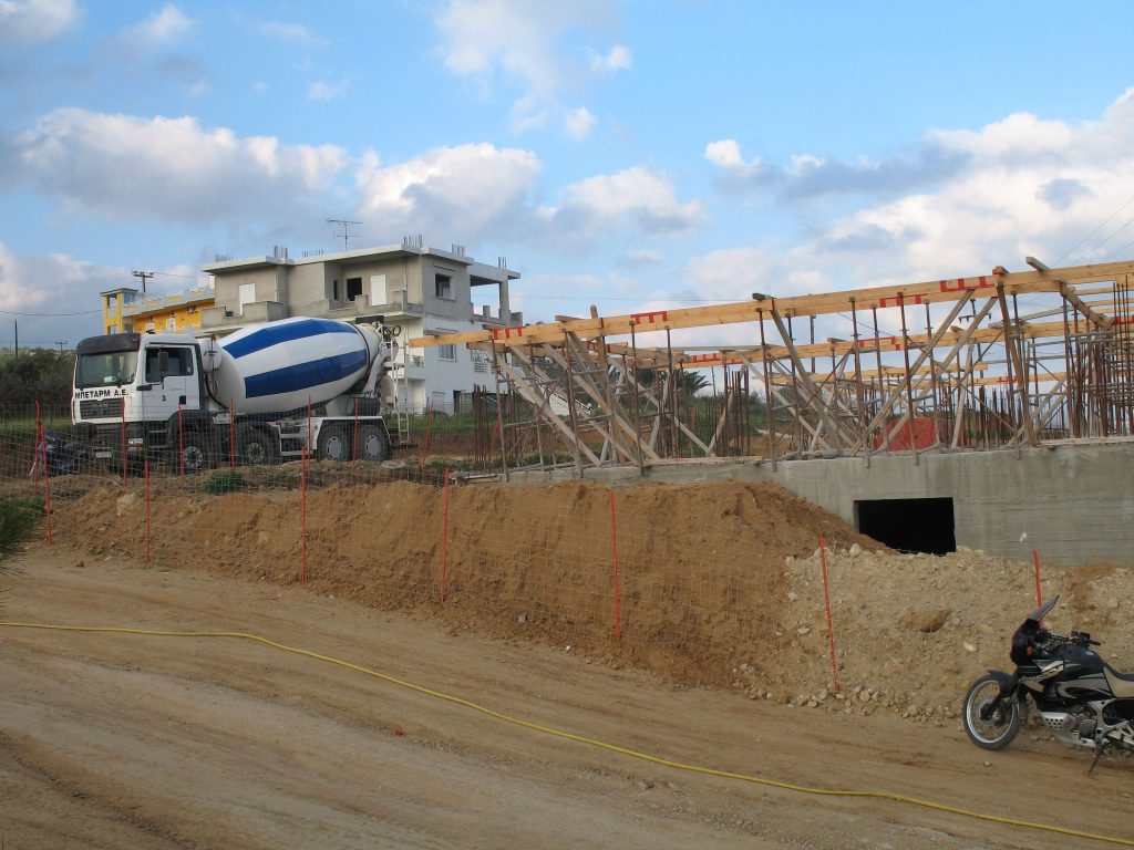 A concrete mixer truck beside the ground-floor formwork and the slopes of the excavation.