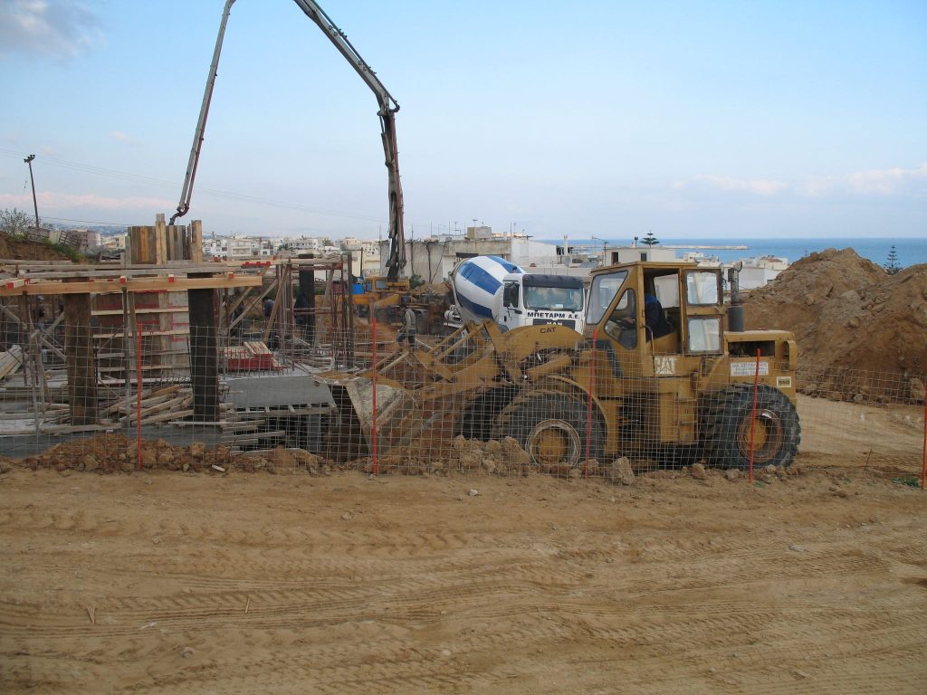 A concrete pump and a loader on site, with the sea in the background.
