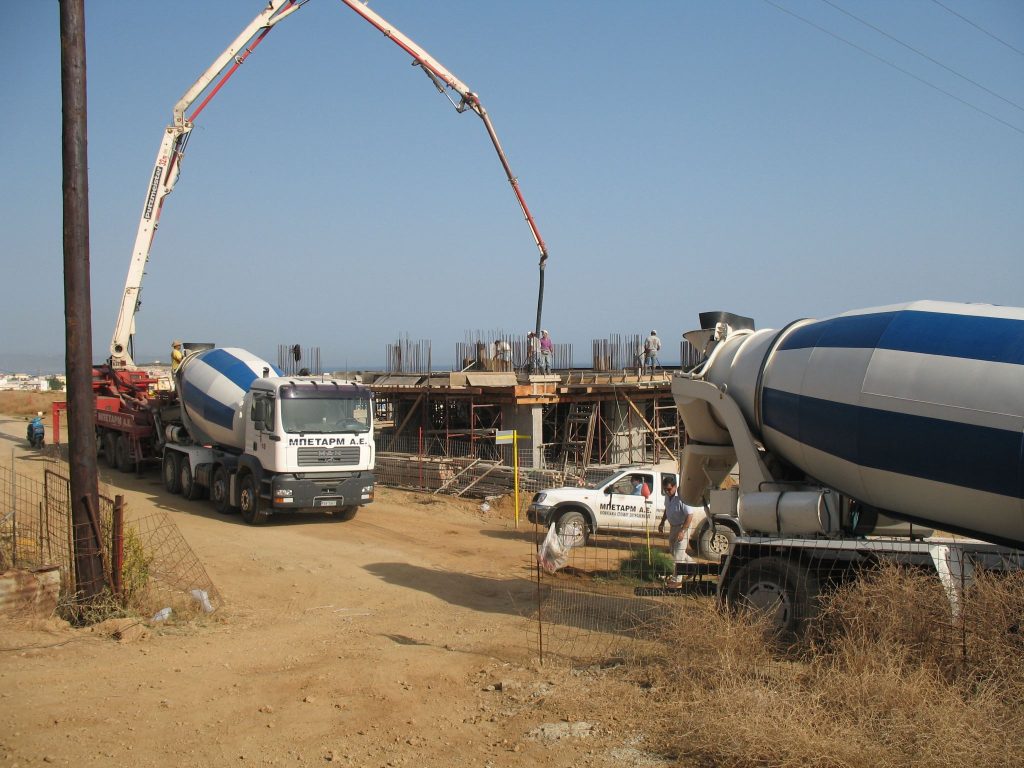 A concrete pump and mixer trucks on site while a floor is being poured.