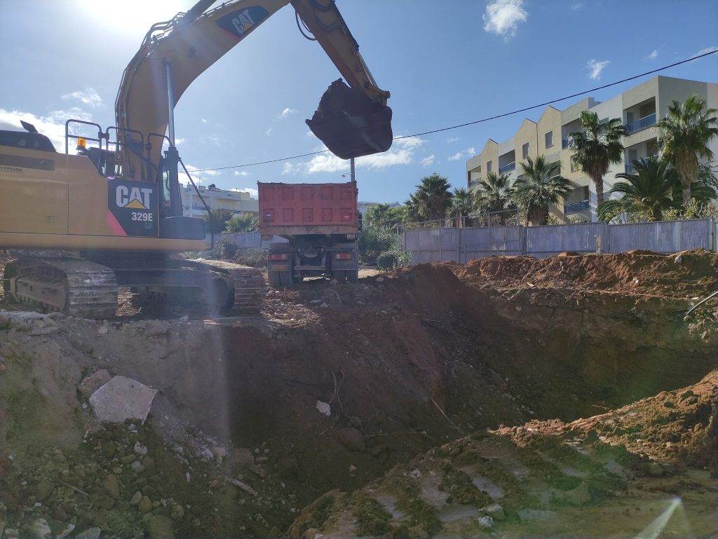 Excavating the plot with an excavator and a truck.