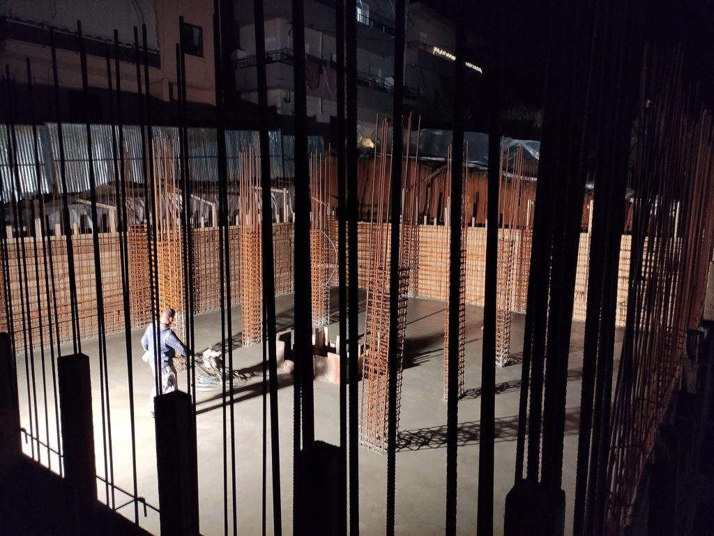 Evening work on the basement floor, among the column reinforcement.