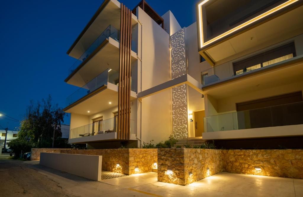 The building's entrance in the evening, with timber louvres, the perforated decorative panel and the lit stonework.