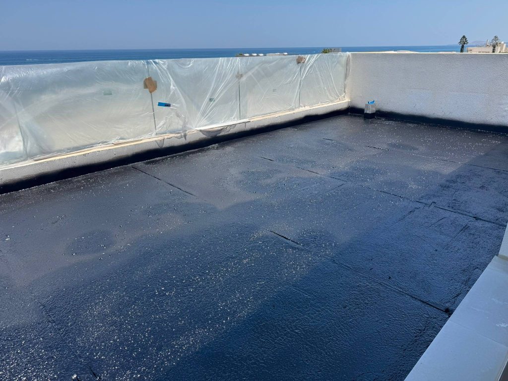 Waterproofing the roof terrace with a bituminous membrane, with a view of the sea.