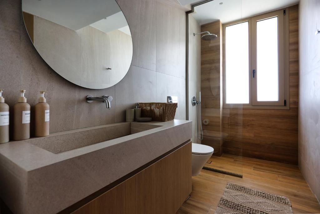 A bathroom with a stone basin, a round mirror and a wood-clad shower.