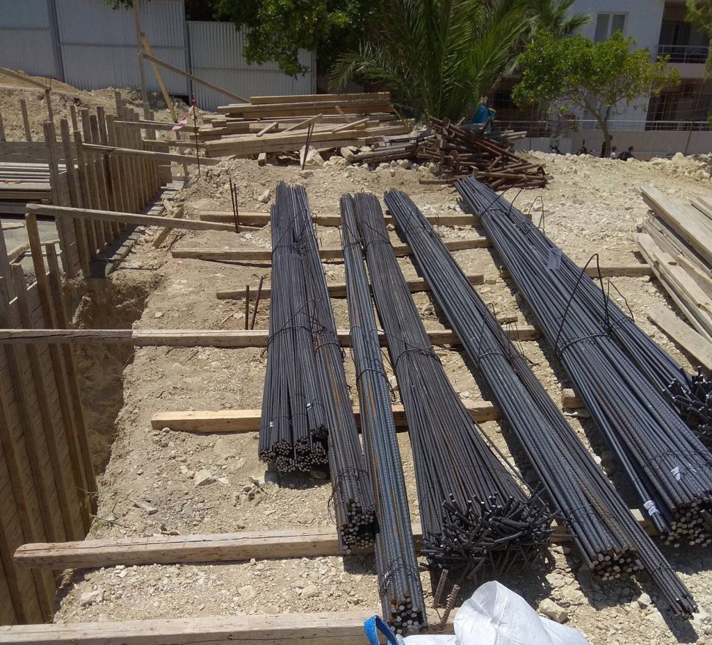 Bundles of reinforcing bars on site, next to the foundation formwork.
