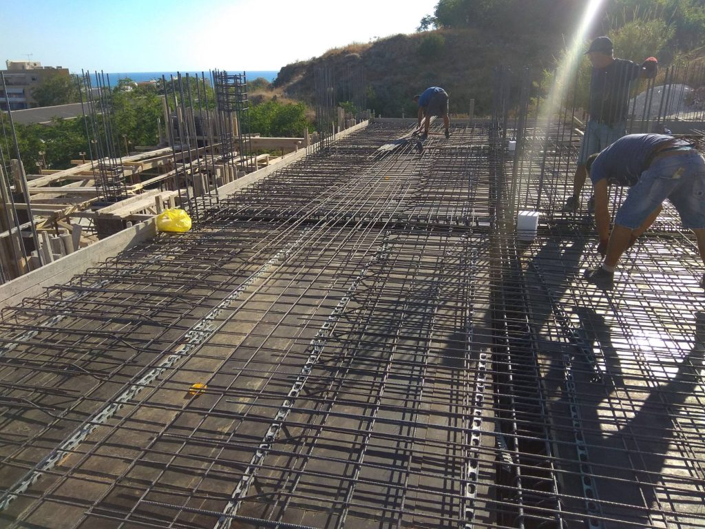 A crew placing the slab reinforcement, with a view of the sea.