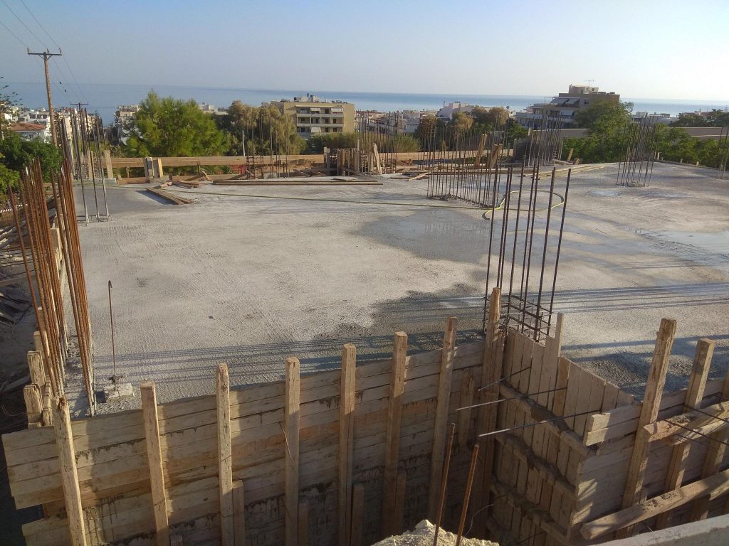 The slab after the concrete pour, with the column starter bars and the town in the background.