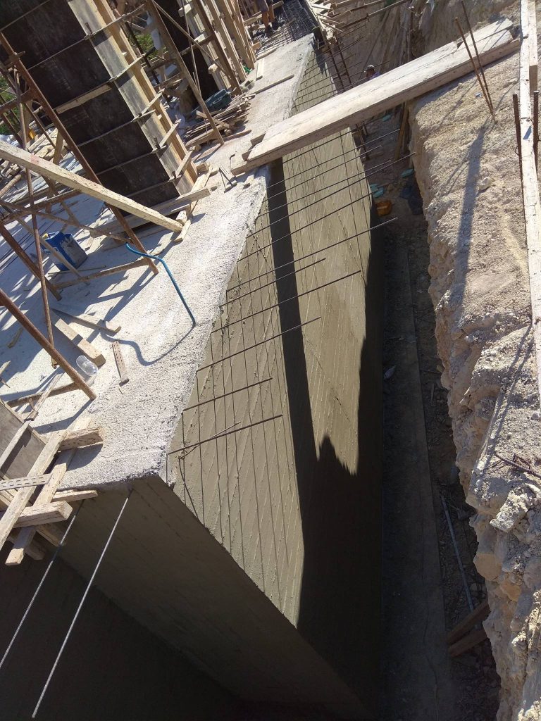 The basement wall from the outside, in the gap between the building and the slope.